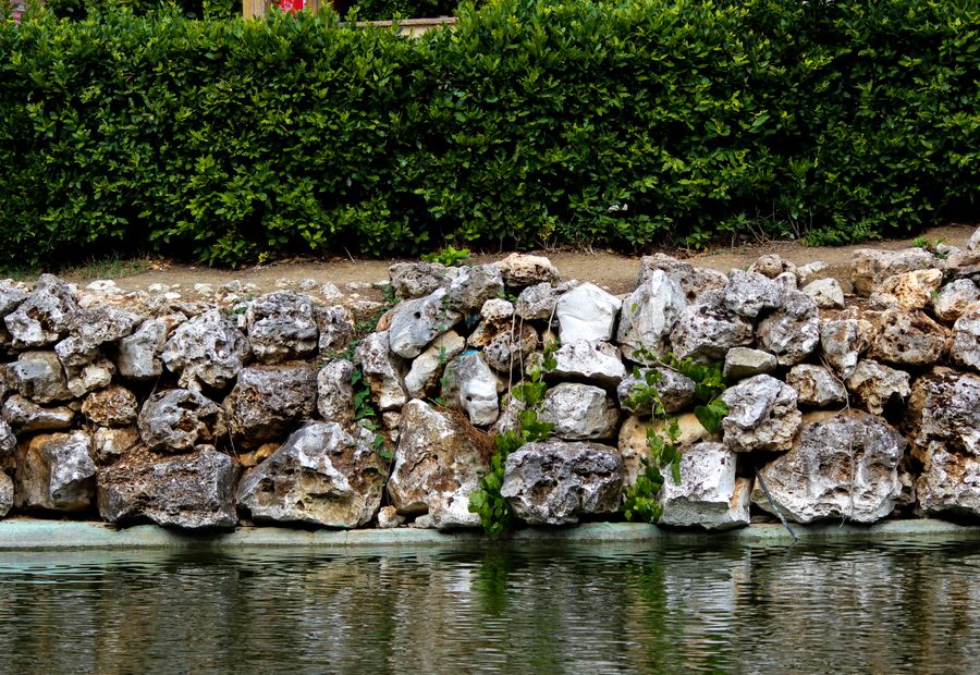Limestone boulder retaining wall set by machine with a buried toe course